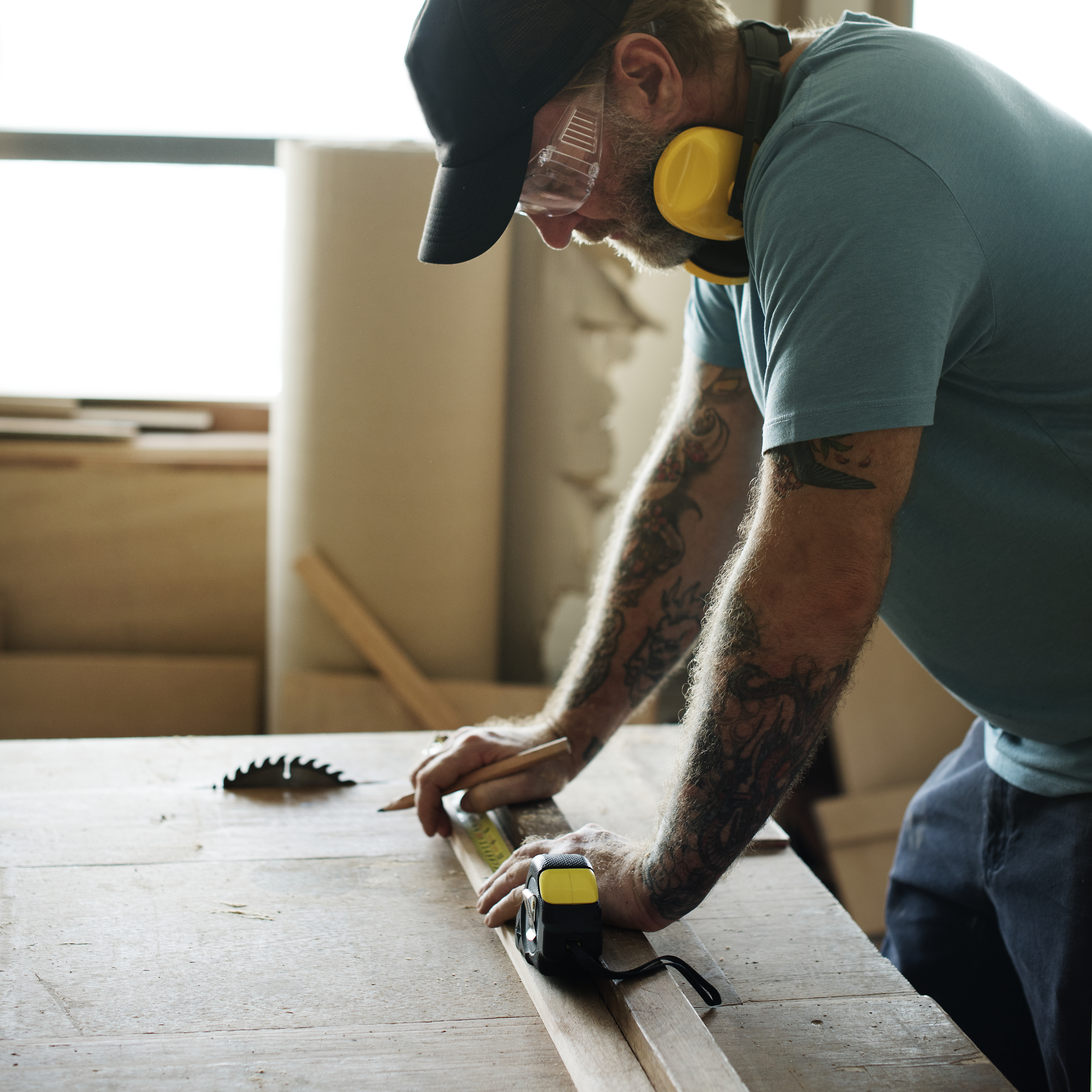 Carpenter using pencil and measurement tape on wood